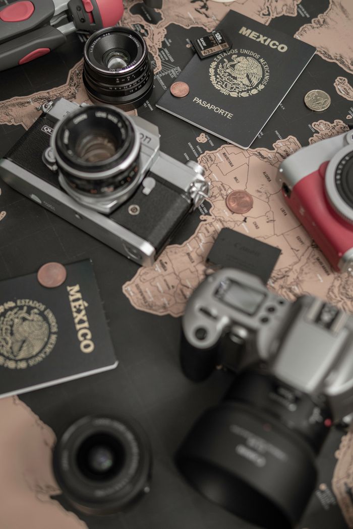 Flat lay of travel essentials including cameras, a map, and Mexican passports.
