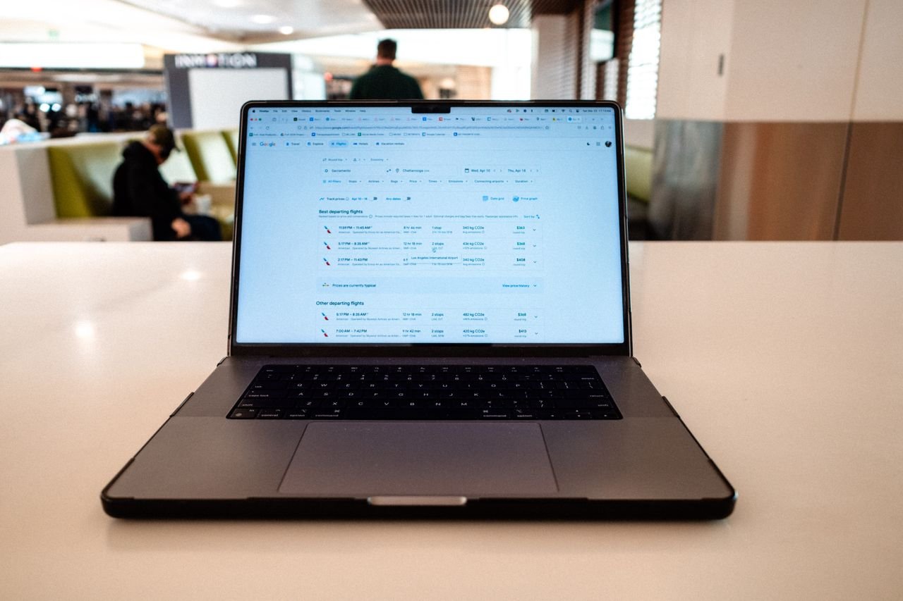 services-02 A modern laptop displaying flight schedules on a white table in an airport lounge.