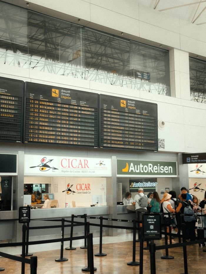 The Art of Drawing Readers In: Your attractive post title goes here Passengers waiting at Cicar and AutoReisen counters in a busy airport in the Canary Islands.